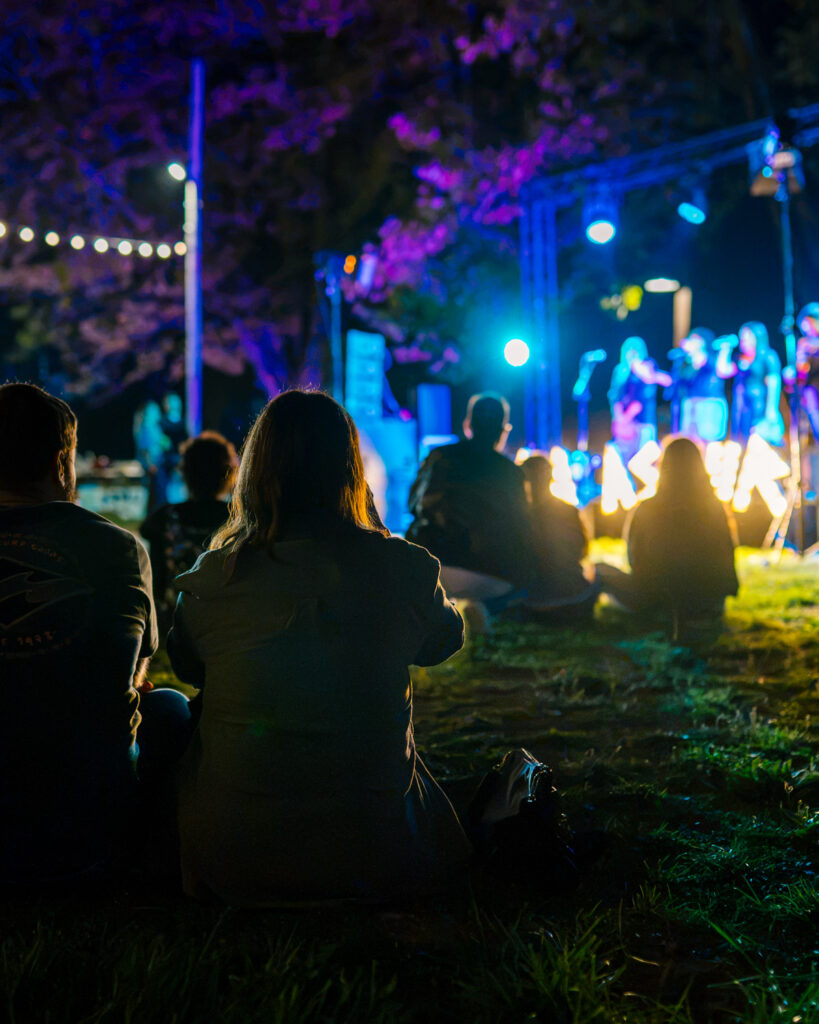GastroPrau Fest Gijón: gente sentada en el prao disfrutando de la música en directo
