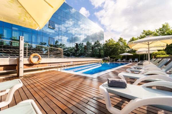 Vista exterior de la terraza con tumbonas y sombrillas en la piscina del Hotel ABBA en Gijón