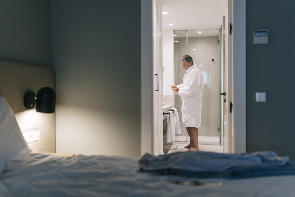 Un hombre en albornoz en el baño de la habitación del hotel