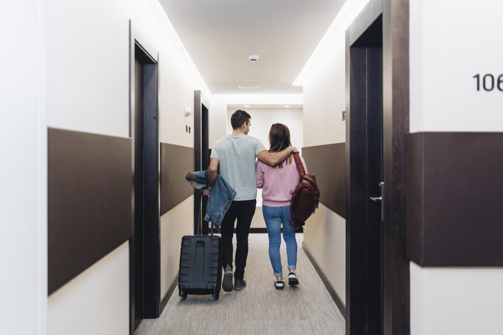 Pareja llegando a una habitación de hotel con sus maletas