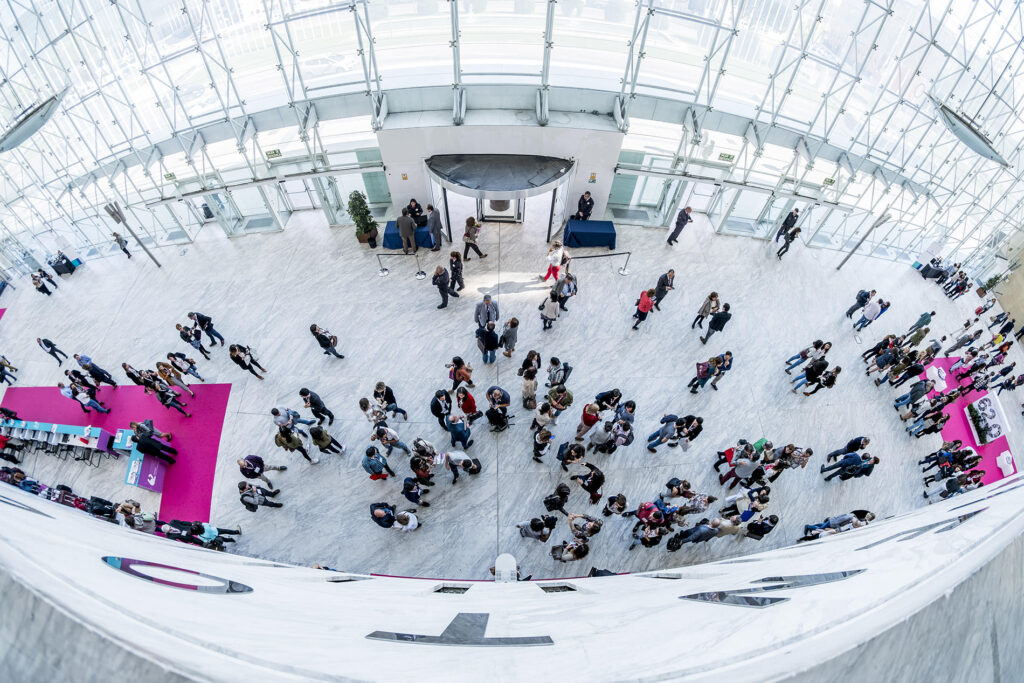 Imagen cenital de mucha gente en un pabellón de exposiciones