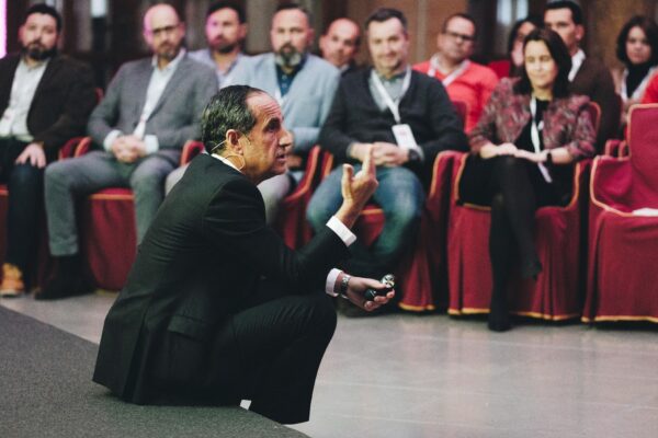 Ponente con micrófono de diadema interviene ante los asistentes durante una conferencia empresarial.